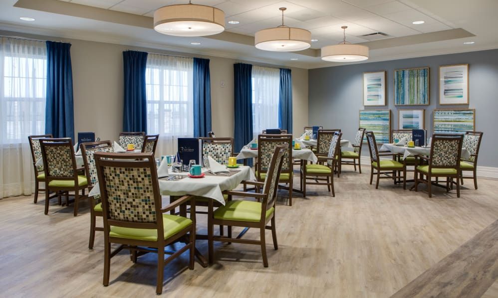 A well-decorated dining room with neatly arranged tables and chairs, illuminated by hanging lights.