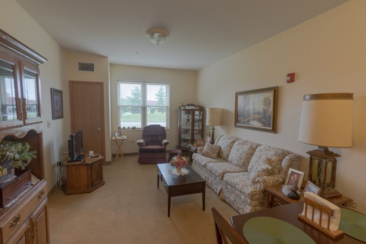 A cozy living room featuring a sofa, coffee table, television, and chair with natural light coming through the window.