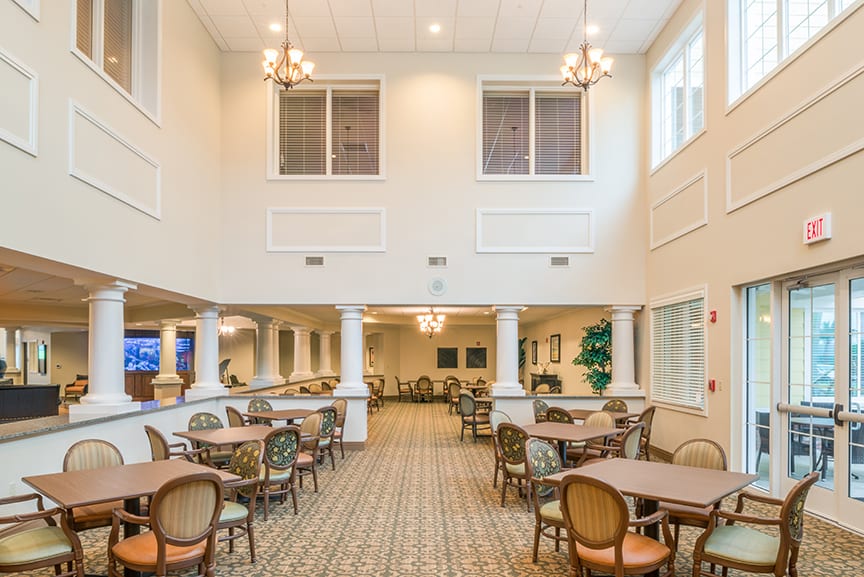 A spacious and well-lit dining area with tables, chairs, and chandeliers.