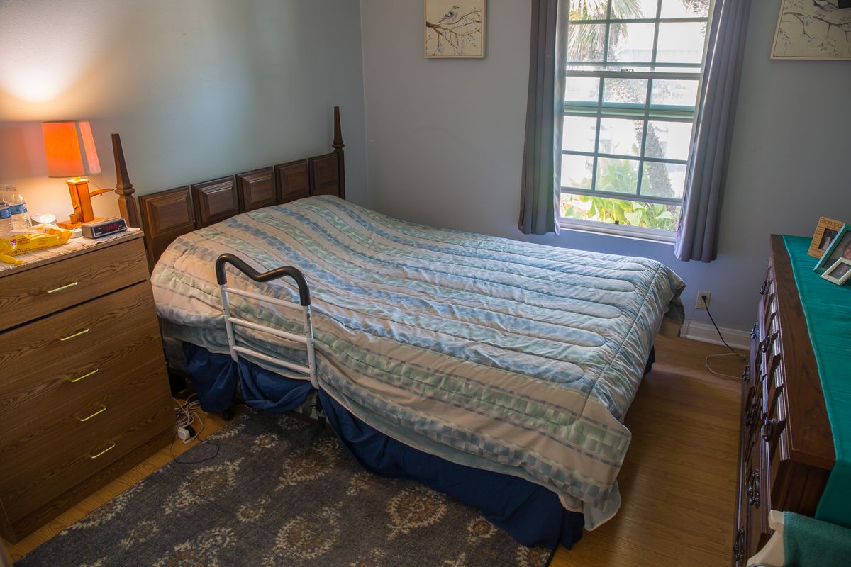 A bedroom with a bed featuring a side rail, next to a window.