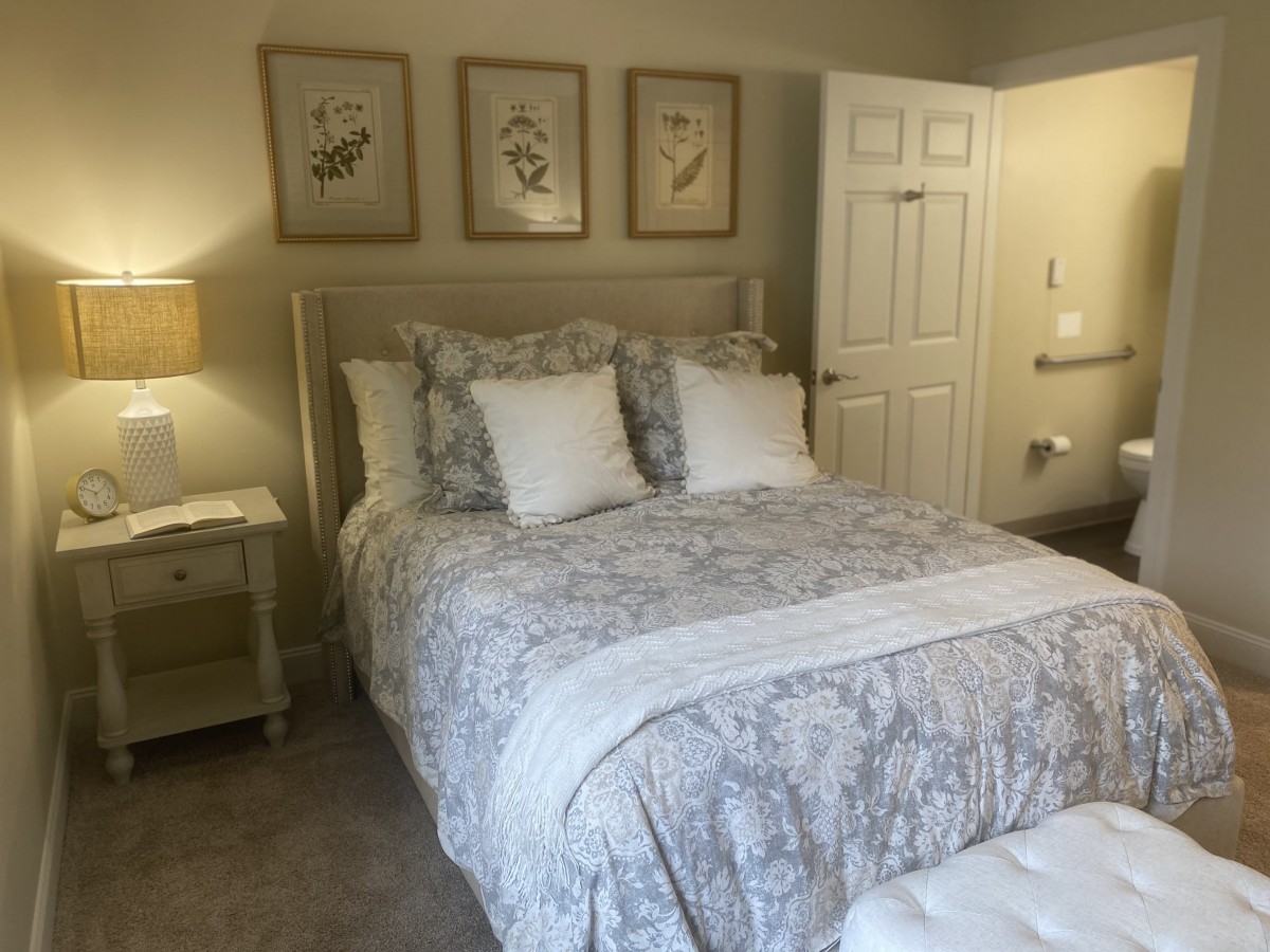 A cozy and elegantly decorated bedroom with a bed, side table, and framed artwork on the wall.