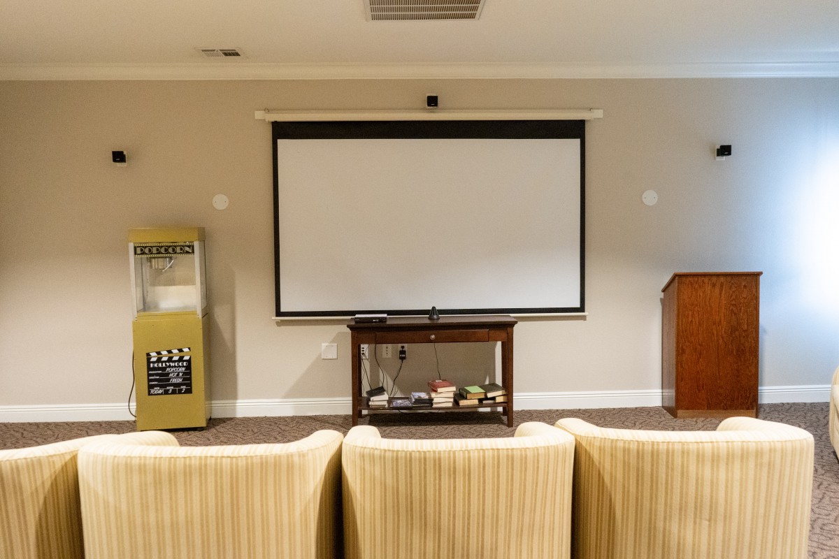 A small presentation room with a screen, podium, and seating area.