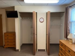An empty room with open closets and wooden furniture.