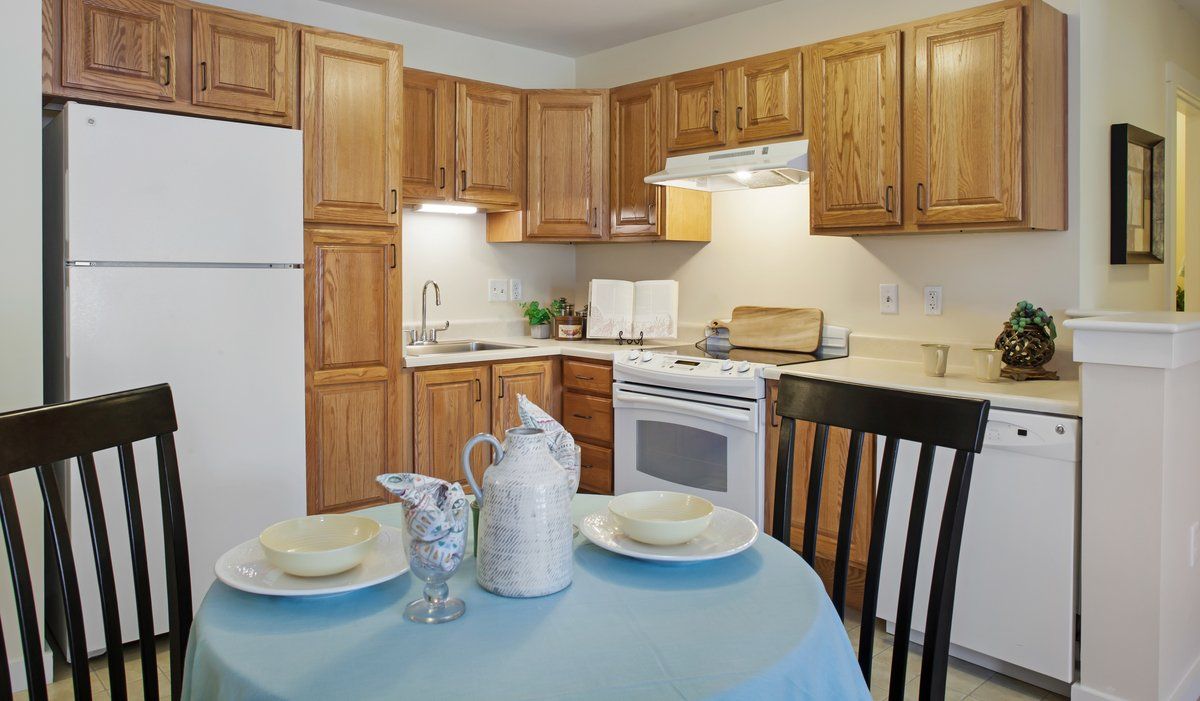 A cozy kitchen with wooden cabinets and a dining table set for two.