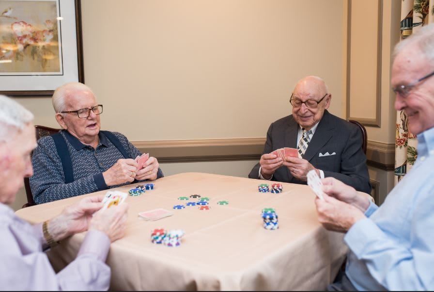 A group of seniors playing poker around a table.