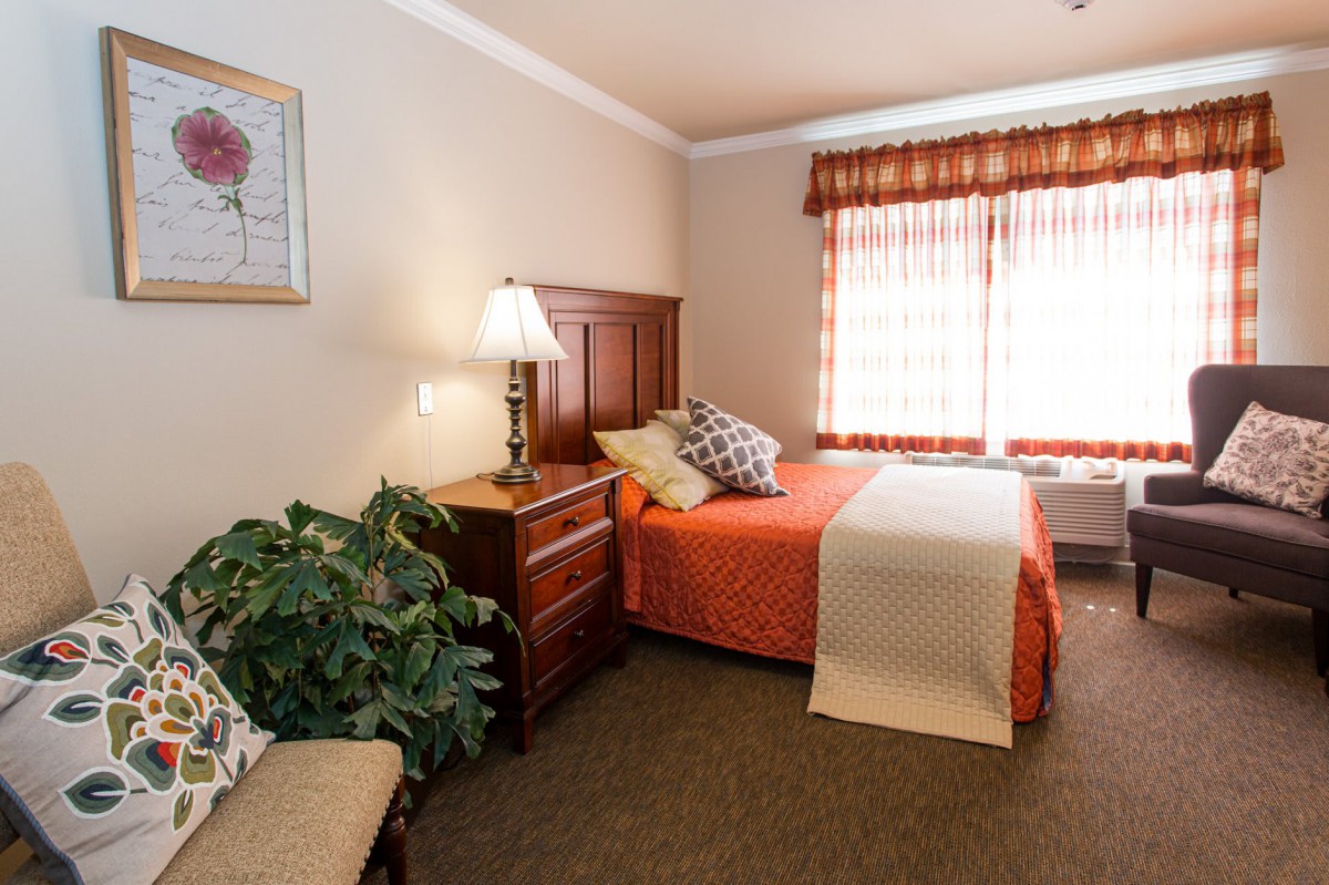 Cozy bedroom with a neatly made bed, a bedside lamp, and decorative accents.