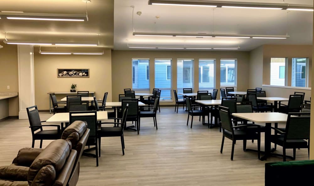 An empty dining room with neatly arranged tables and chairs, illuminated by overhead lights.