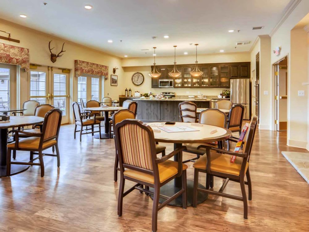 A spacious dining and kitchen area with multiple tables and chairs, featuring a hardwood floor and modern lighting.