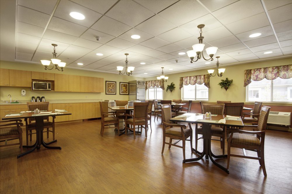 A spacious dining room with wooden tables and chairs, adorned with elegant lighting fixtures.