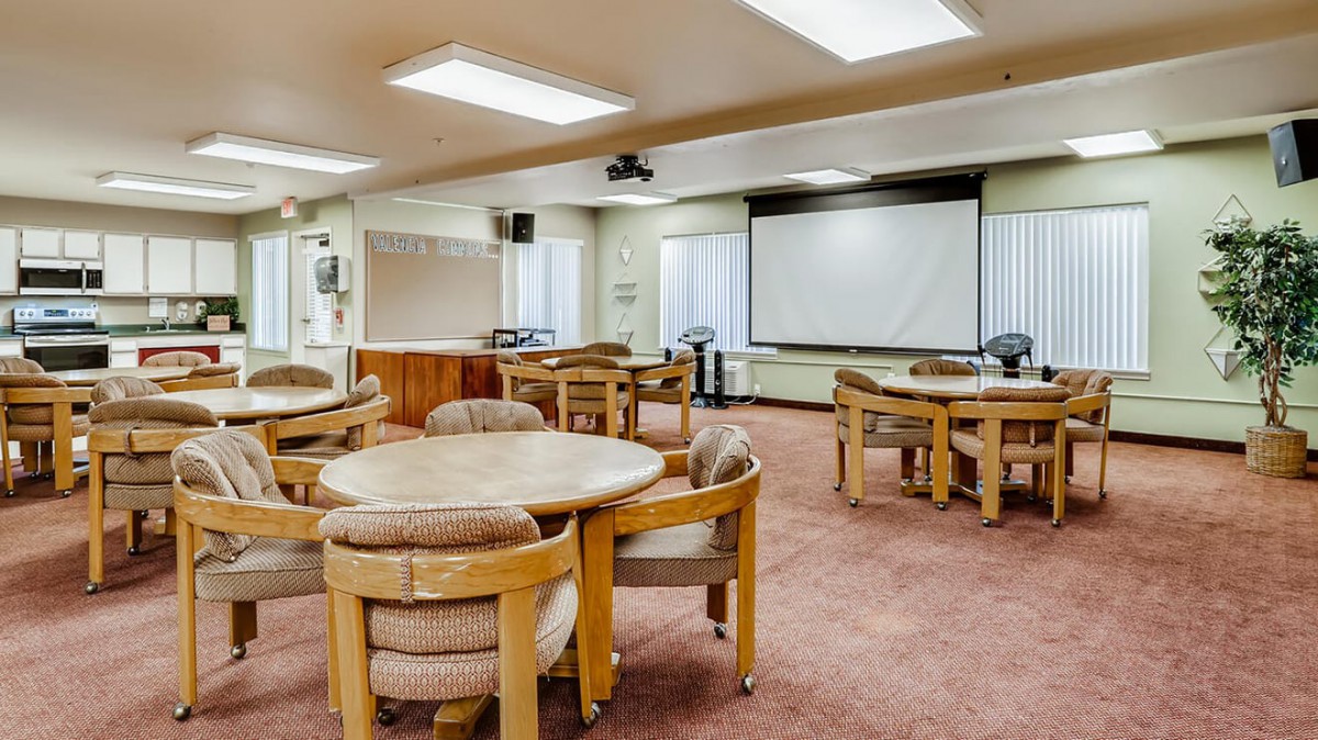 An empty conference room with round tables and a large projector screen.