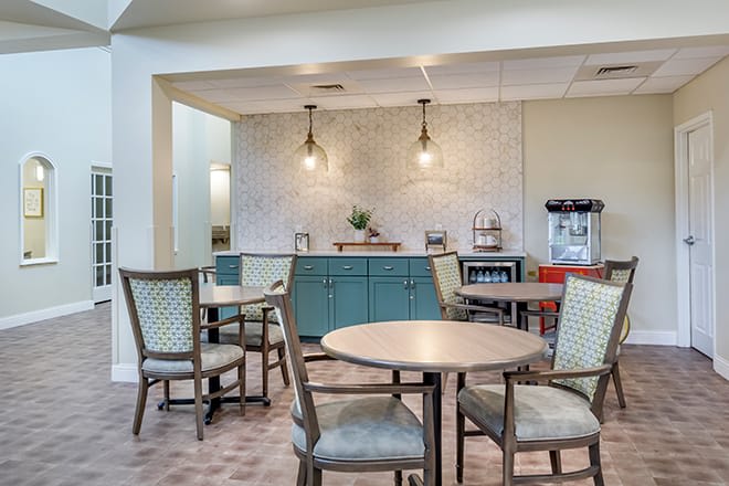 A cozy cafe interior featuring round tables, comfortable chairs, and stylish lighting.