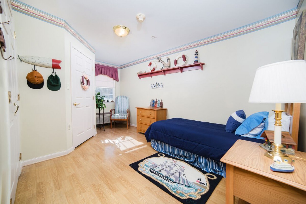 A nautical-themed bedroom with a single bed, wooden floor, and various decorations.