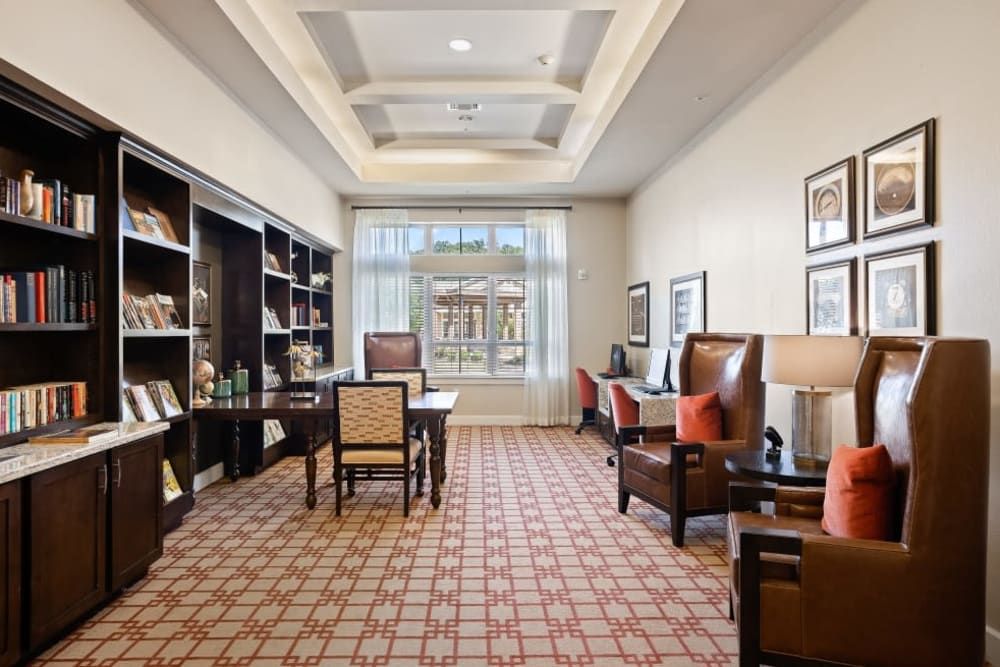A cozy library with bookshelves, comfortable seating, and a large window letting in natural light.