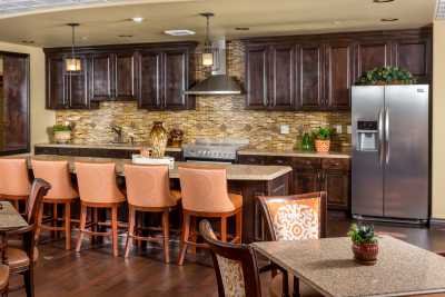 A modern kitchen with a central island, bar stools, and stainless steel appliances.