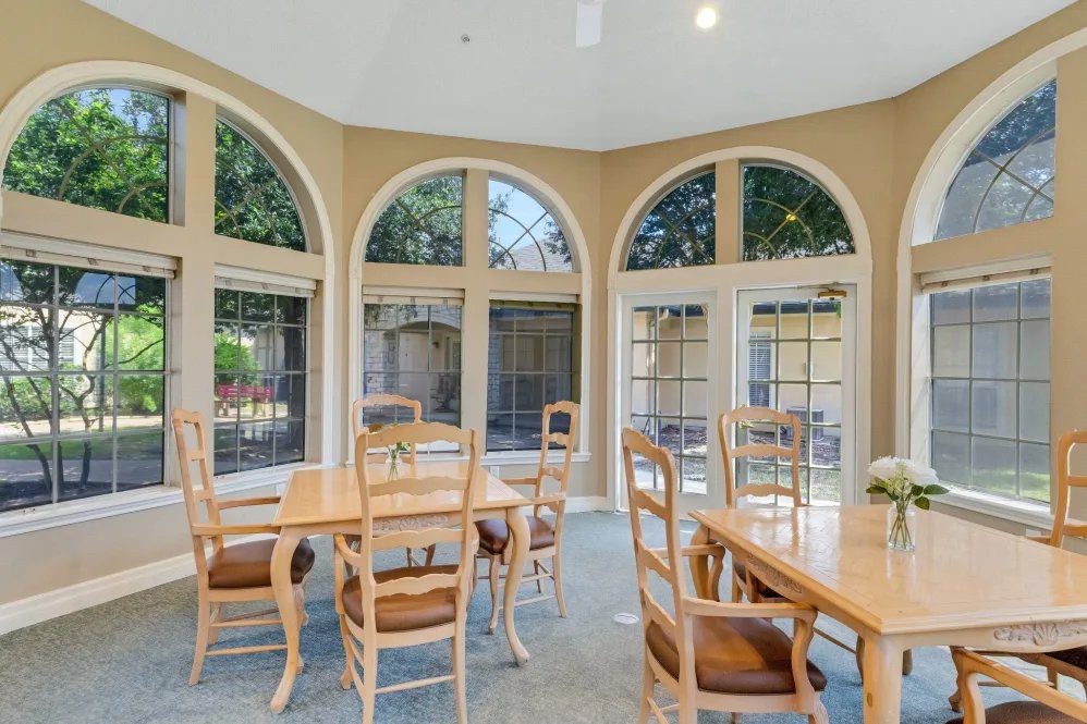 A well-lit dining area with large arched windows and wooden furniture.