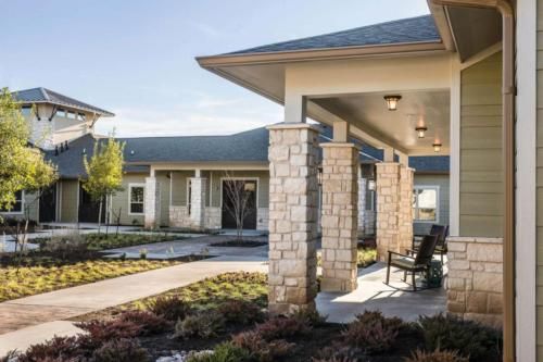 A modern building with stone pillars and a landscaped pathway.