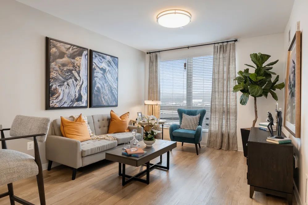 A modern living room with contemporary decor, featuring a comfortable sofa, an armchair, artwork on the walls, and abundant natural light.