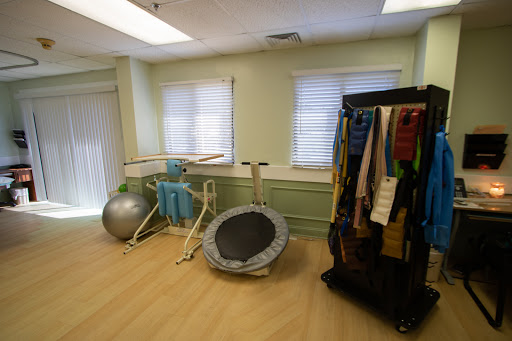 A well-equipped exercise room featuring a trampoline, balance balls, and therapy bands for rehabilitation and fitness activities.