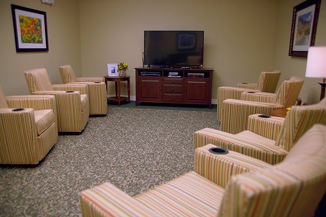 A cozy lounge area with striped chairs arranged in front of a large television.