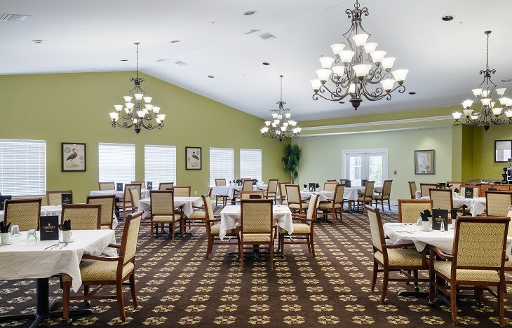 An elegant dining room with chandeliers, neatly arranged tables and chairs.