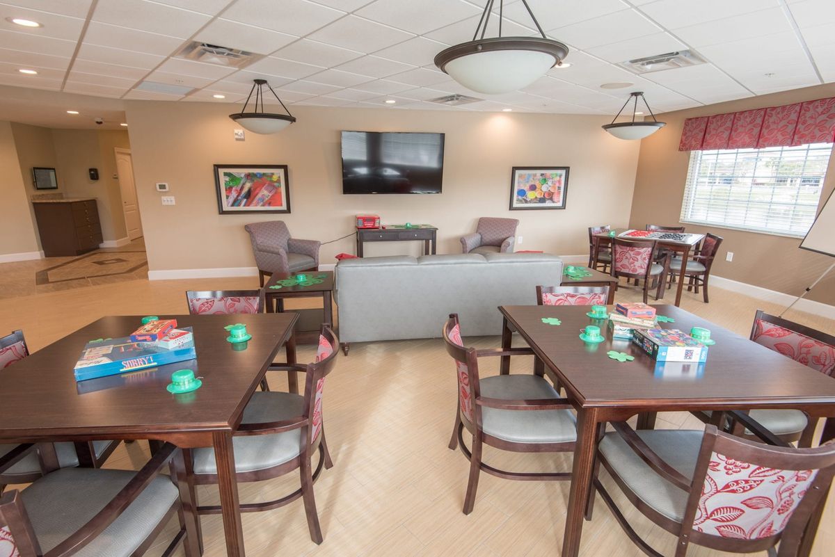 A comfortable recreational room with tables and chairs, a sofa, a television, and various games available for entertainment.