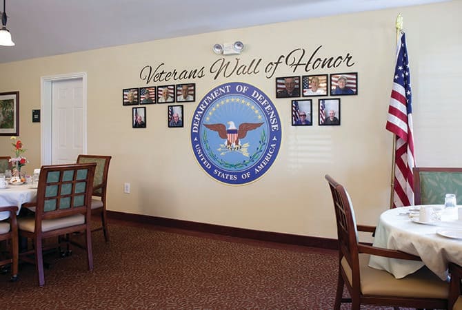 A wall dedicated to honoring military veterans, featuring photographs and an emblem, titled 'Veterans Wall of Honor'.