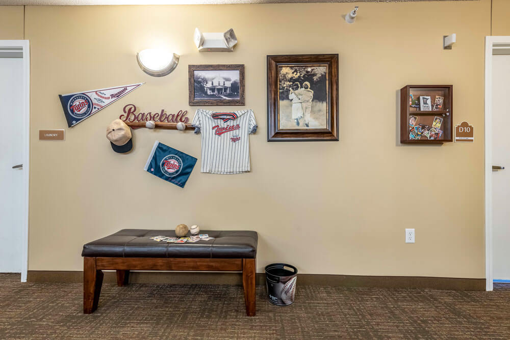 A sports-themed room featuring baseball memorabilia and decor on the walls, accompanied by a wooden bench below.