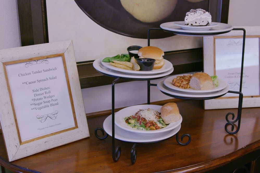A tiered display of various dishes including a sandwich, salad, and a dessert in a restaurant setting.