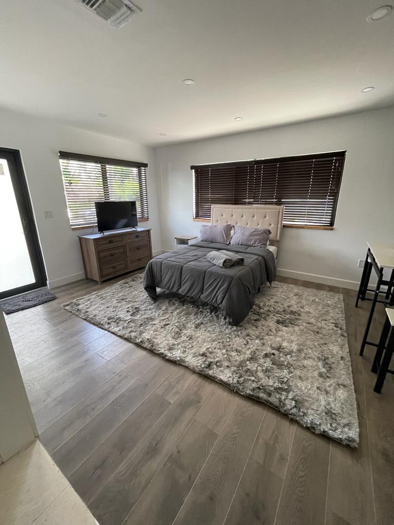 A modern bedroom with a cozy bed, stylish rug, and sleek furniture.