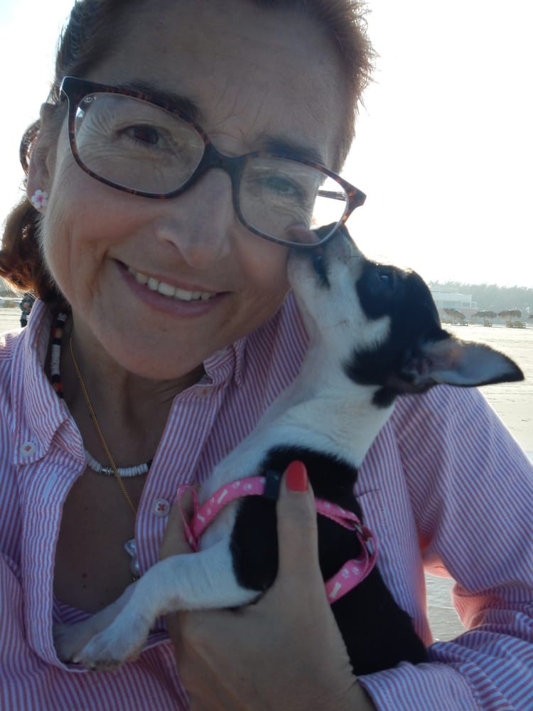 A woman wearing glasses takes a selfie with her dog outdoors.