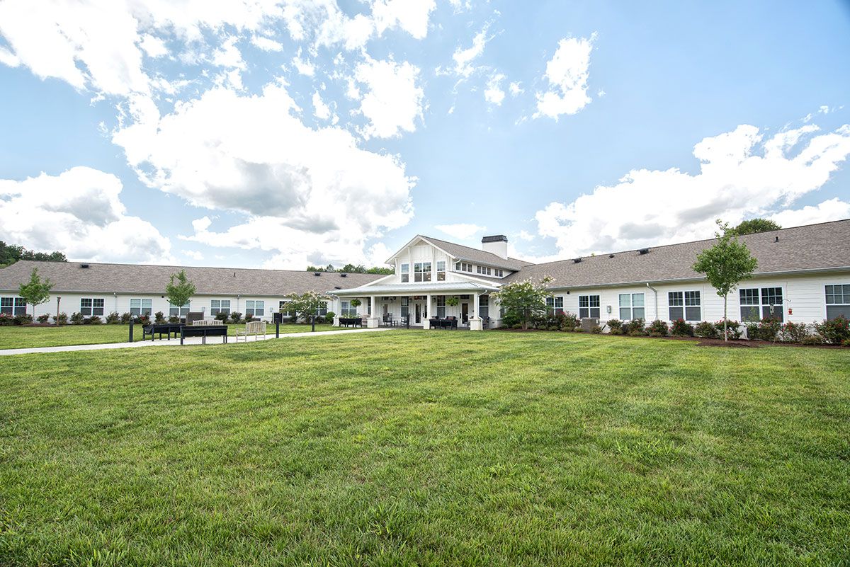 A large house with a well-maintained lawn under a partly cloudy sky.