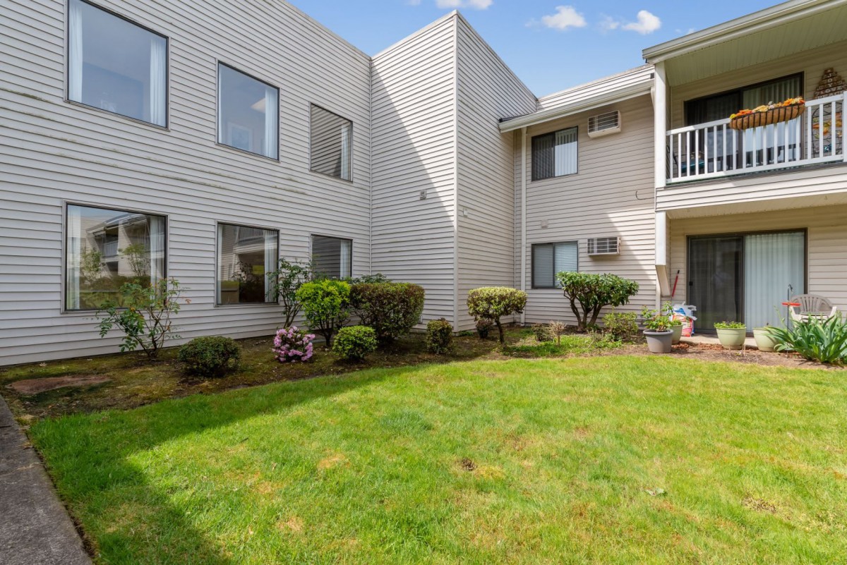A well-maintained apartment building with a green lawn and landscaped garden.