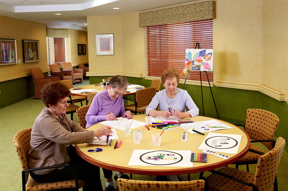 A group of seniors participates in an art class, enjoying drawing and painting activities at a community center.