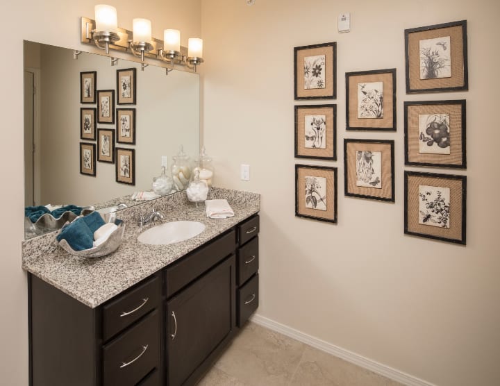 A stylish bathroom with granite countertop and framed wall art.