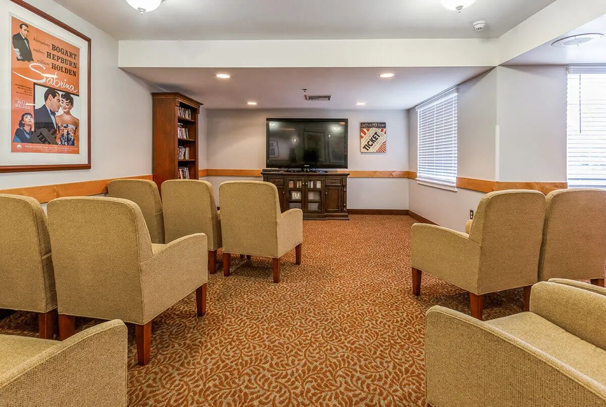 A comfortable conference room with beige chairs facing a large television.