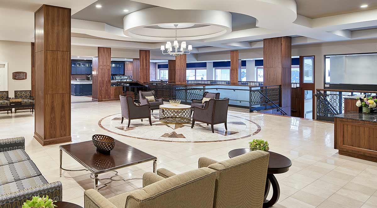 A modern hotel lobby featuring a comfortable seating area with elegant furniture and a stylish chandelier.