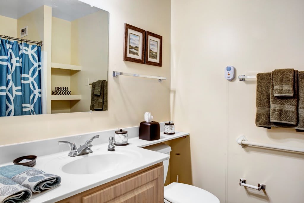 A clean and well-organized bathroom with a sink, mirror, and neatly arranged toiletries.