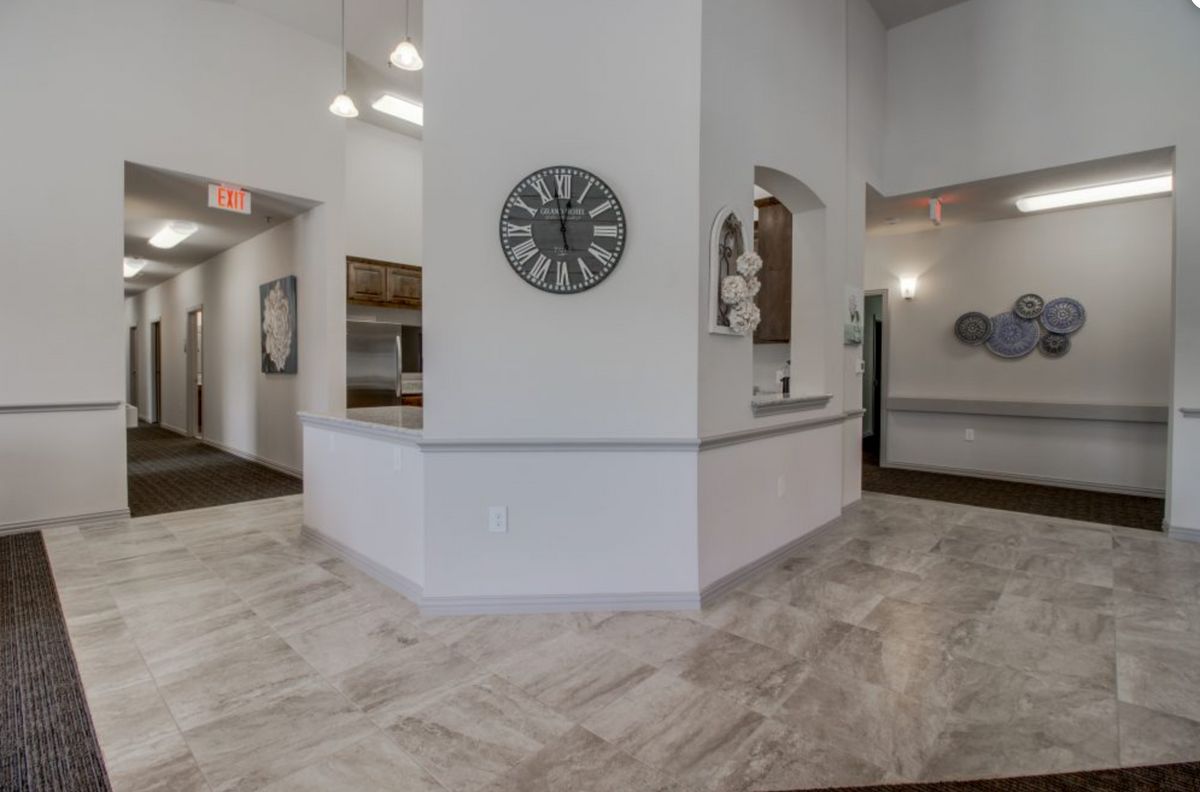 A modern lobby with a reception area featuring white walls and tile flooring, decorated with a wall clock.