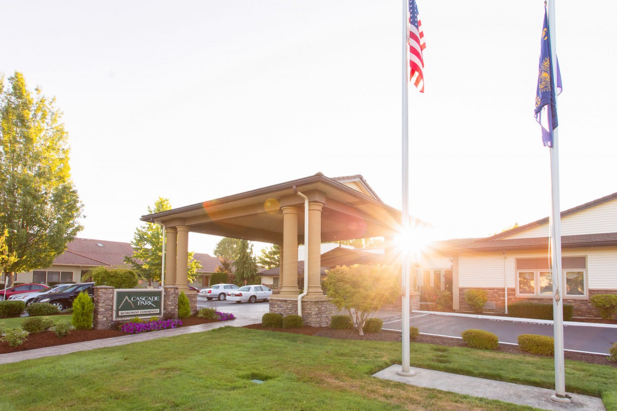 A building entrance with a flagpole during sunset, surrounded by well-maintained landscaping.