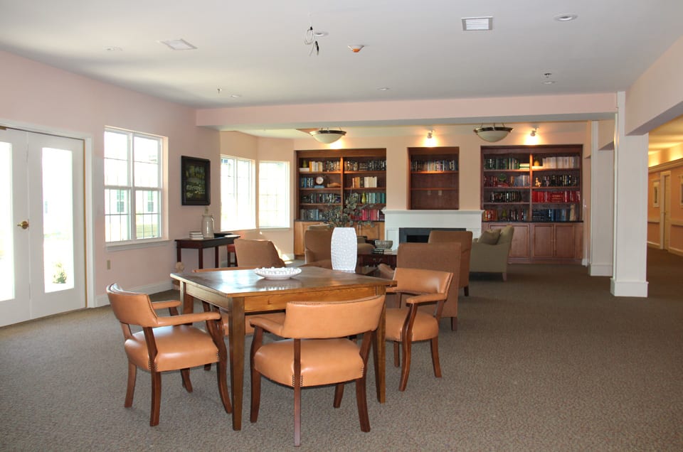 A cozy library space with a table, chairs, and bookshelves filled with books.