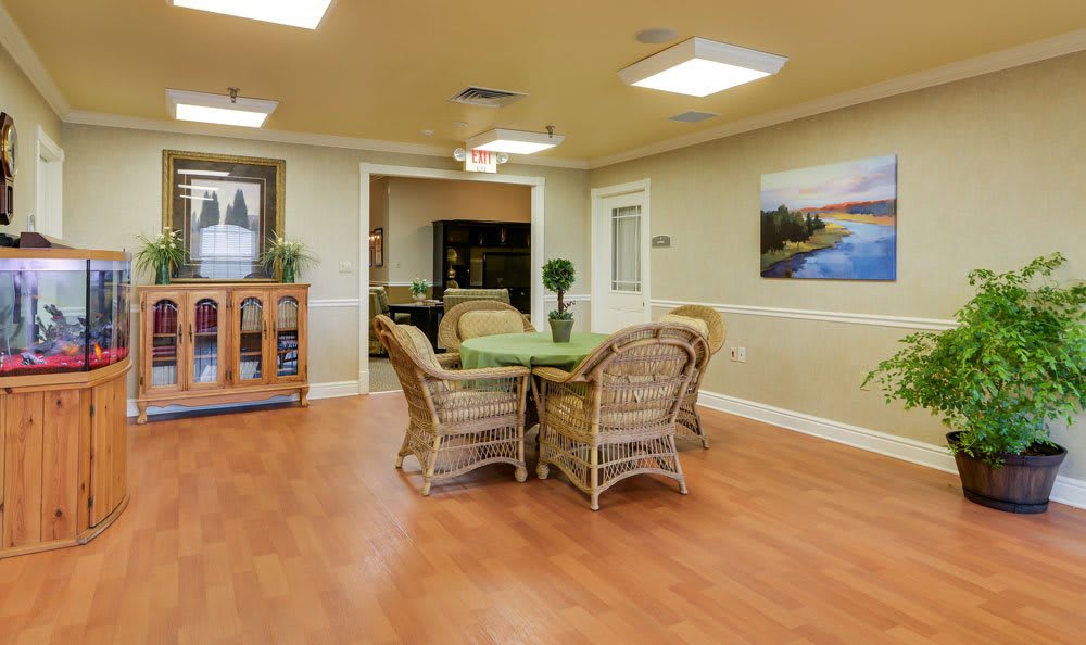 A cozy dining area featuring a round table surrounded by wicker chairs, set on a warm wooden floor with decorative wall art.