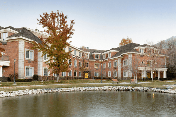 A brick building with a scenic view of a lake and autumn trees.