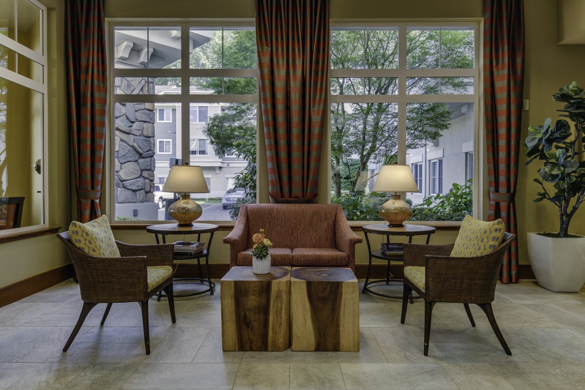 A cozy living room setup with a sofa, chairs, and lamps by the window.
