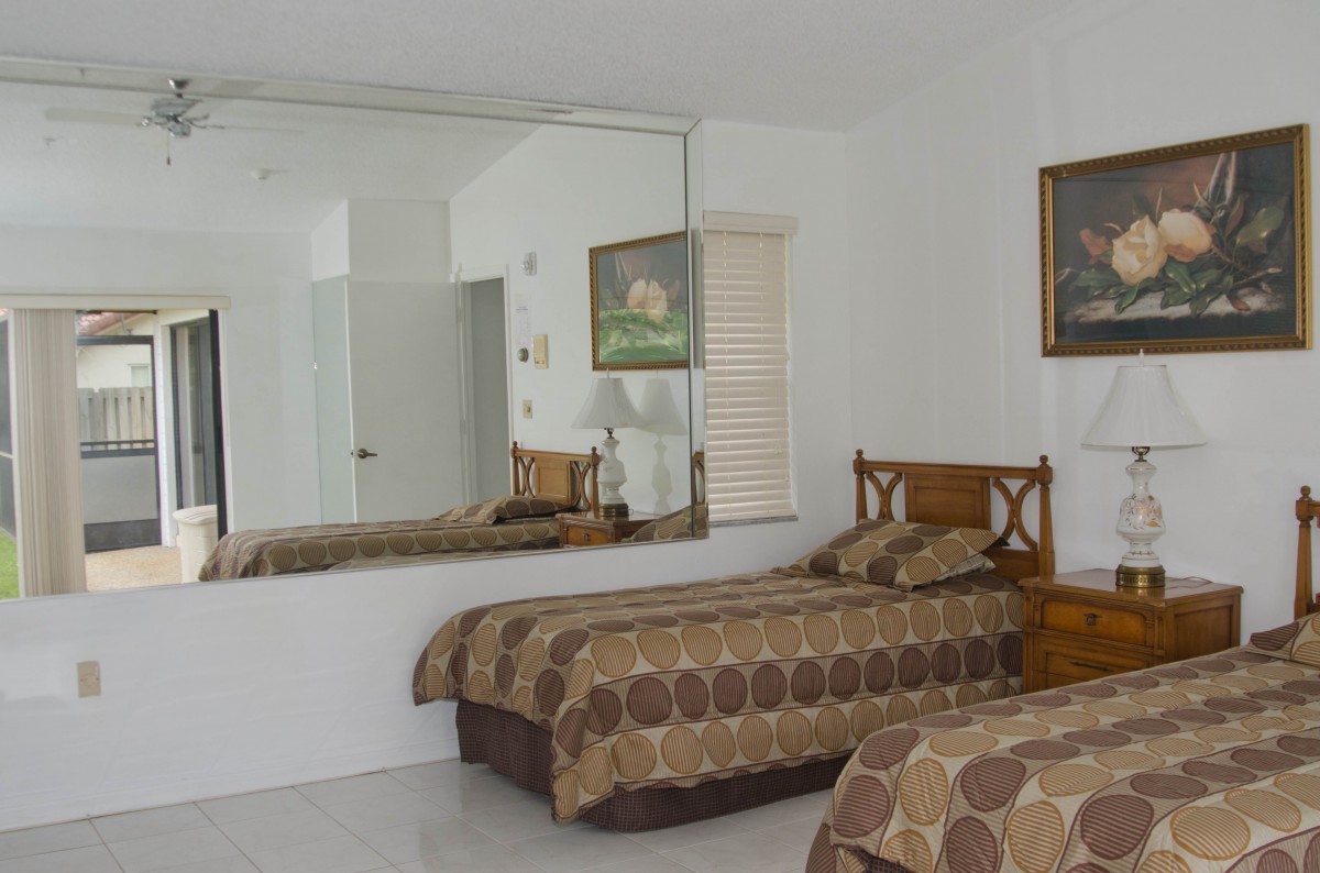 A bedroom with a large mirror, twin beds, and decorative artwork.