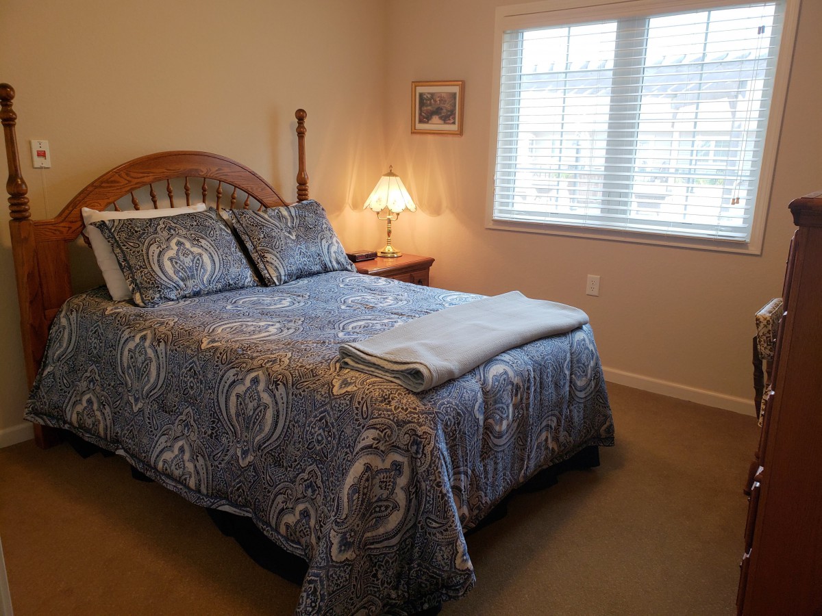 A cozy bedroom with a neatly made bed and a bedside lamp.