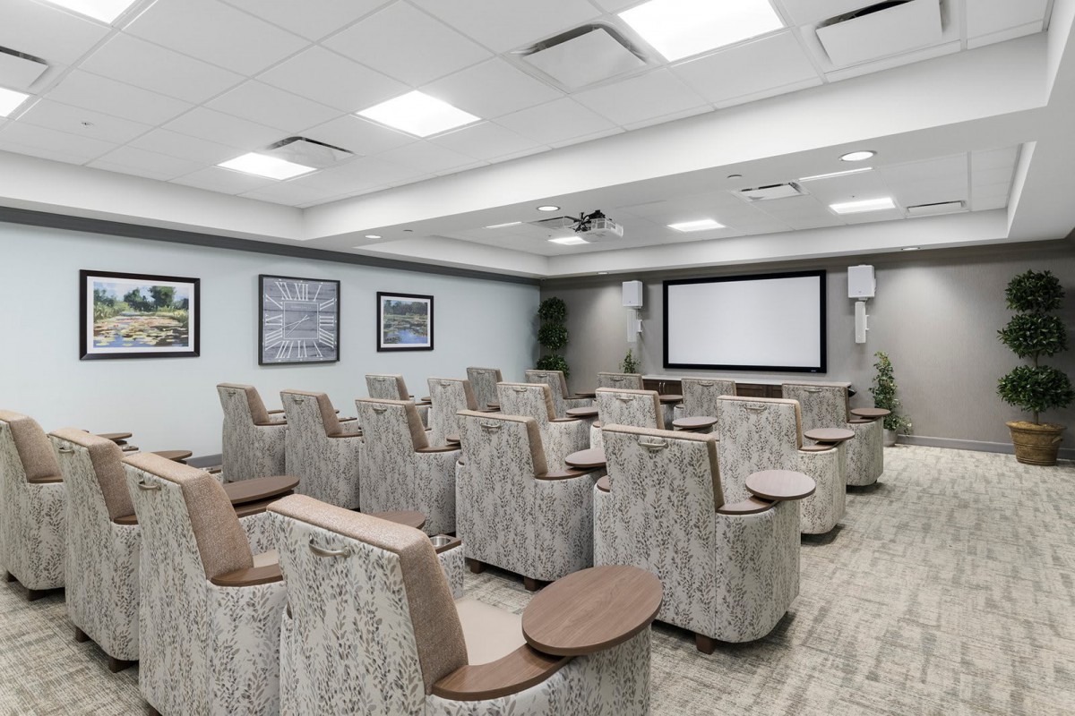A modern theater-style conference room with comfortable seating and a large projector screen.