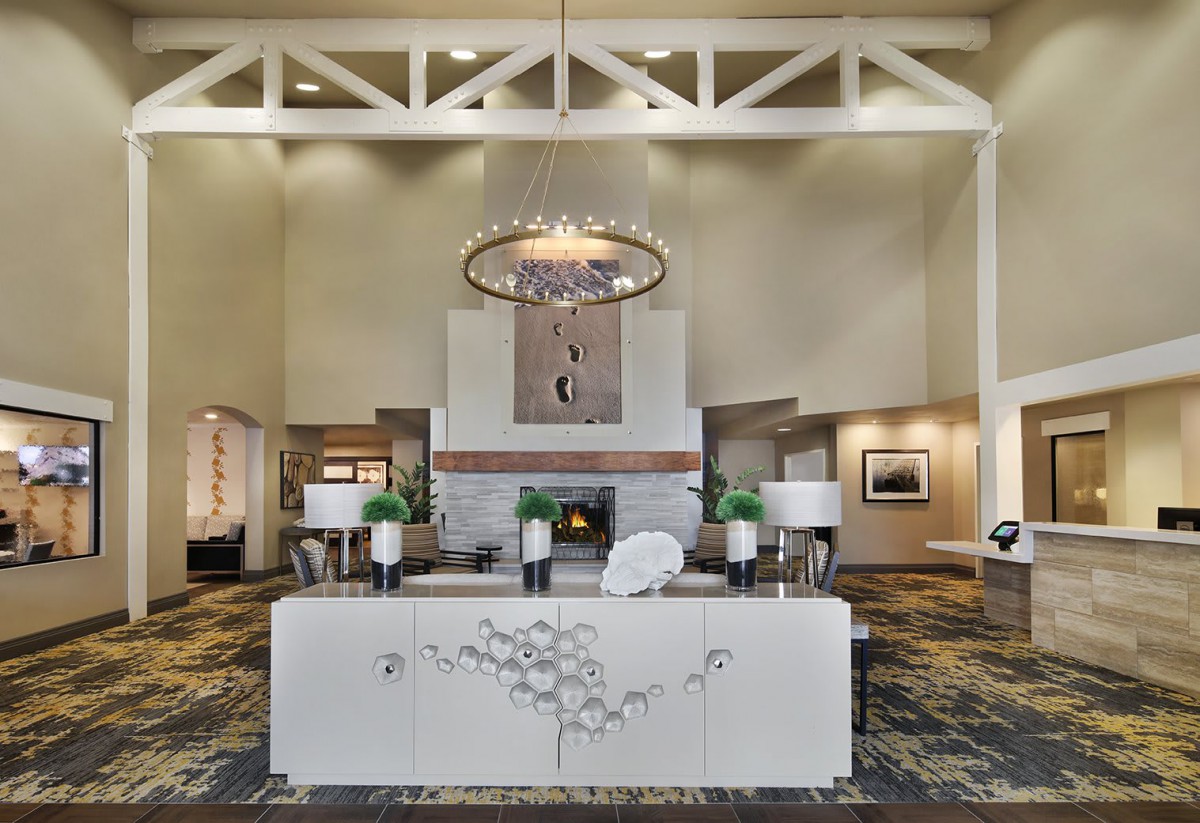 A modern hotel lobby featuring a grand chandelier and stylish reception desk.