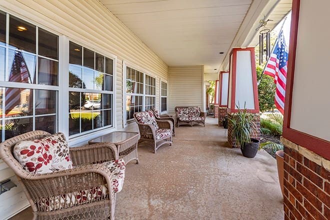 A cozy porch with wicker chairs and a flag.