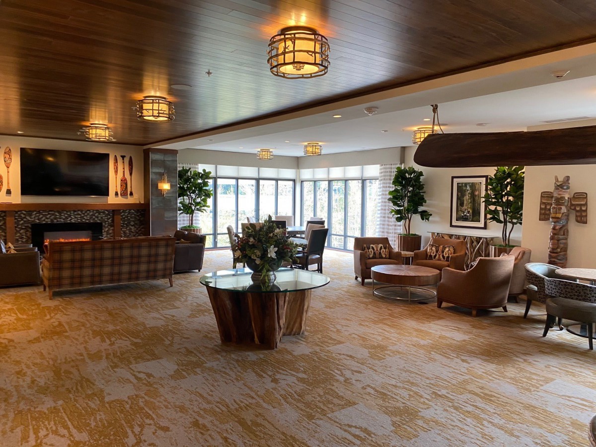 A modern and spacious lobby featuring comfortable seating, indoor plants, and ample natural light from large windows.