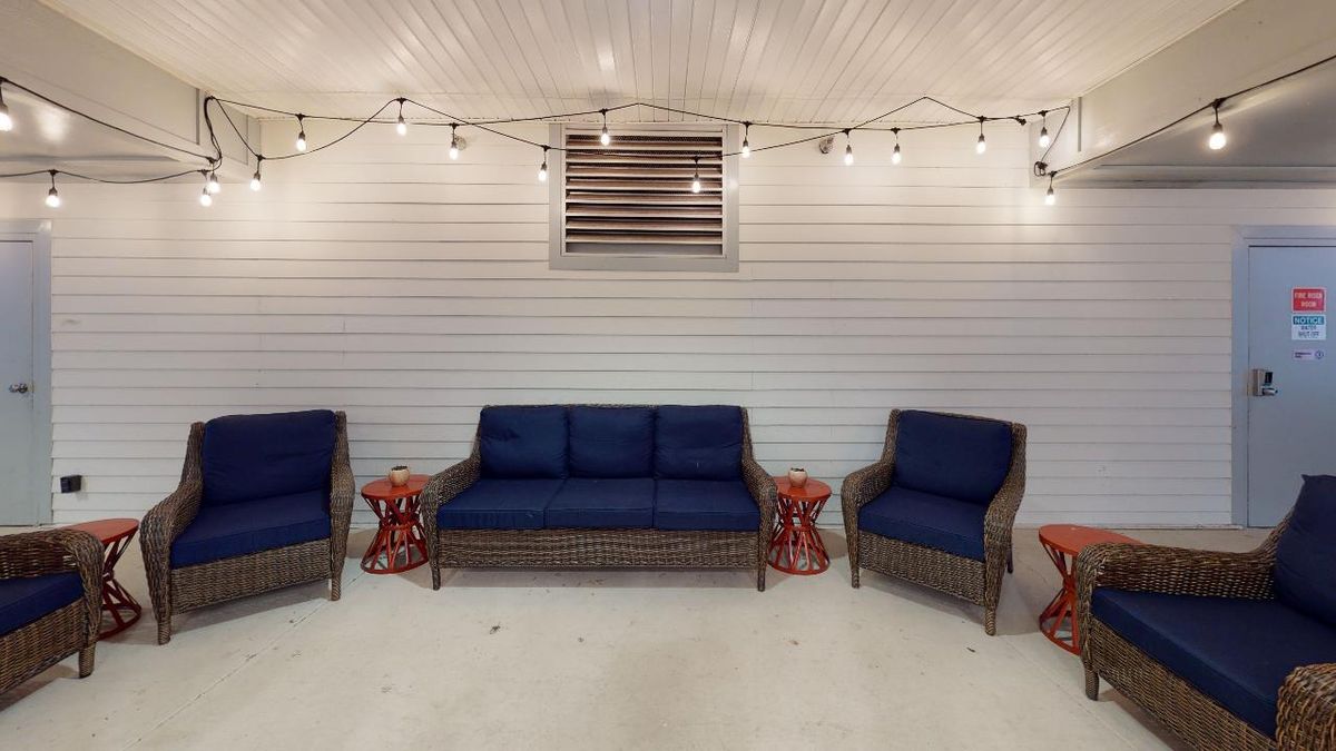 A cozy patio setup with navy blue cushioned seating and decorative string lights.